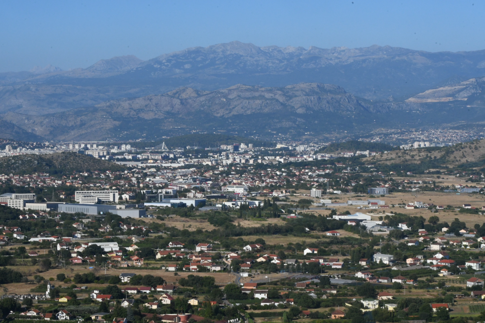 Panoráma Podgorice s nízkou zástavbou a pohorím na horizonte