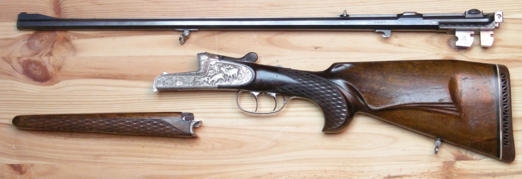 Rozložená jednohlavňová poľovná zbraň s odňatou hlavňou položená na drevenom stole